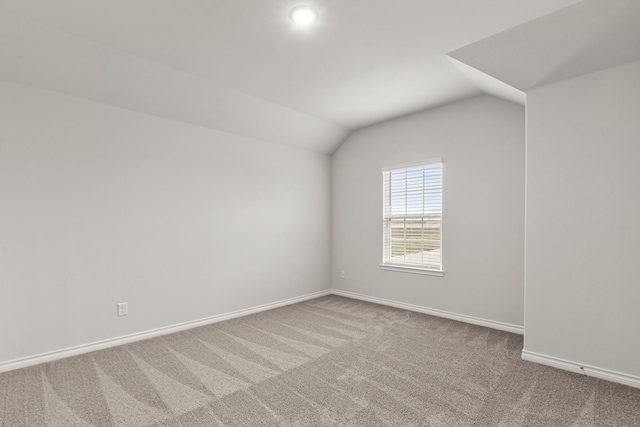 unfurnished room featuring carpet floors and vaulted ceiling