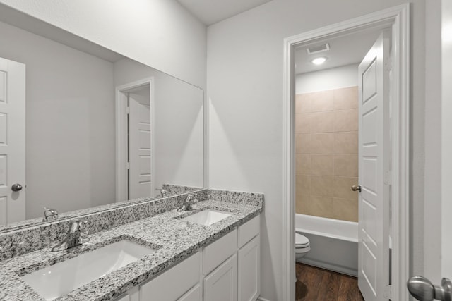 full bathroom with vanity, toilet, tiled shower / bath combo, and hardwood / wood-style floors