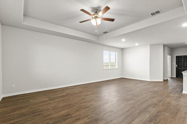 spare room featuring ceiling fan, a tray ceiling, and dark hardwood / wood-style flooring