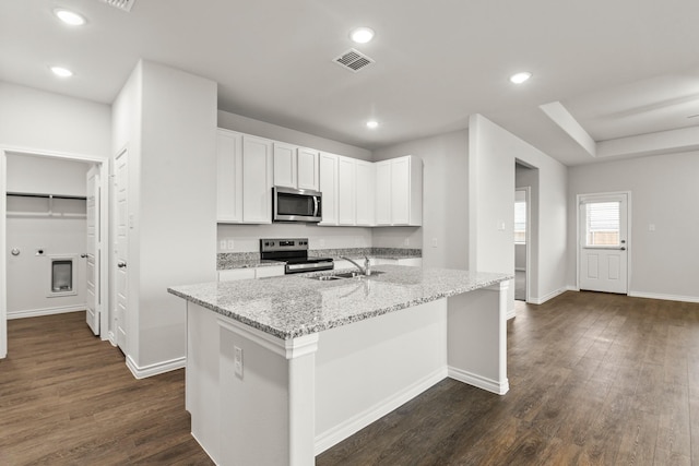 kitchen featuring sink, light stone counters, a center island with sink, stainless steel appliances, and white cabinets