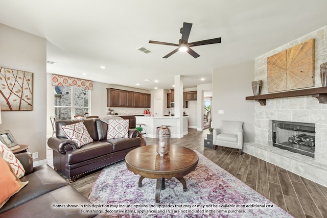 living room featuring ceiling fan, dark hardwood / wood-style floors, and a fireplace