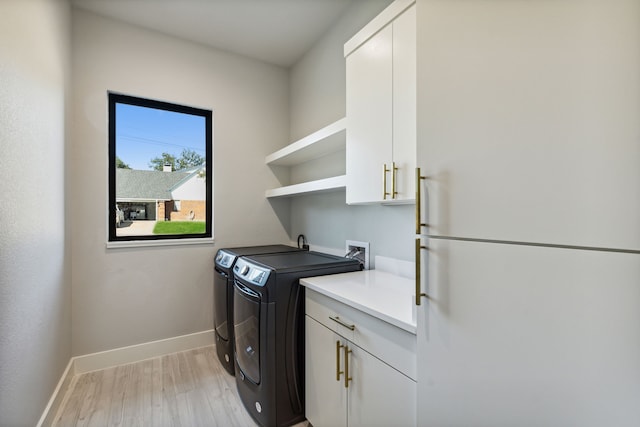 laundry area featuring light hardwood / wood-style flooring, independent washer and dryer, and cabinets