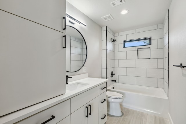 full bathroom featuring toilet, tiled shower / bath, and vanity