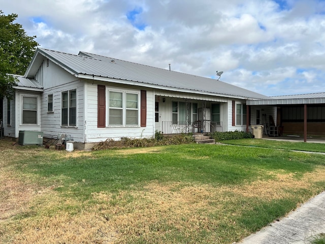 rear view of property featuring central AC unit, covered porch, and a lawn