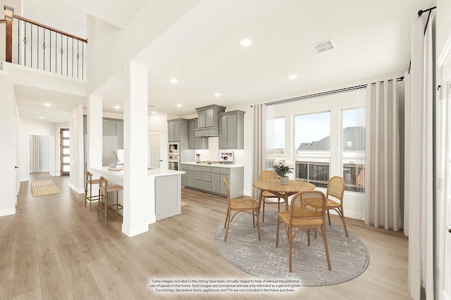 kitchen with gray cabinets, light hardwood / wood-style floors, appliances with stainless steel finishes, and a breakfast bar