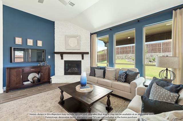 living room featuring brick wall, lofted ceiling, hardwood / wood-style floors, and a stone fireplace