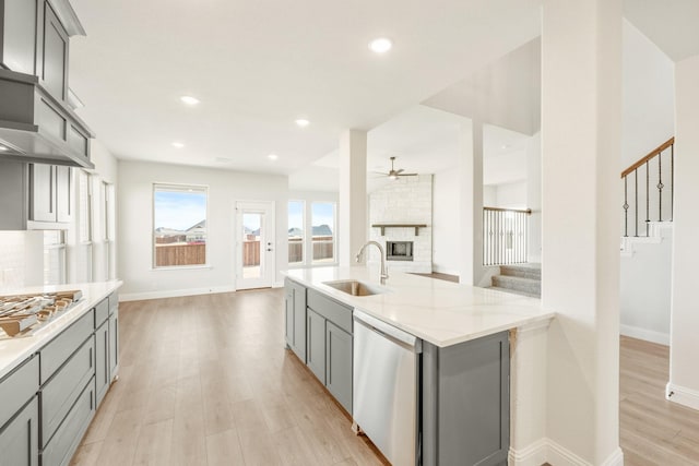 kitchen featuring appliances with stainless steel finishes, sink, light stone counters, gray cabinetry, and light hardwood / wood-style floors