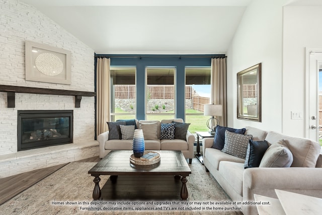 living room with hardwood / wood-style floors, a stone fireplace, and lofted ceiling