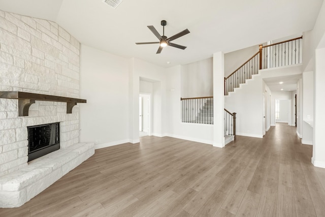 unfurnished living room with a fireplace, ceiling fan, light wood-type flooring, and high vaulted ceiling