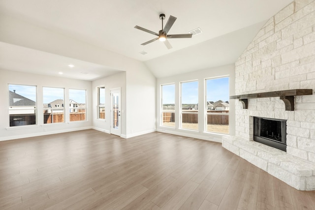 unfurnished living room with ceiling fan, a stone fireplace, vaulted ceiling, and hardwood / wood-style floors