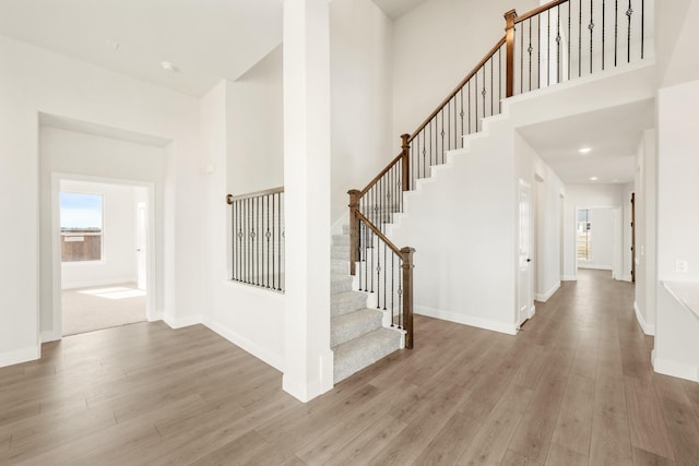 staircase with hardwood / wood-style flooring and a towering ceiling