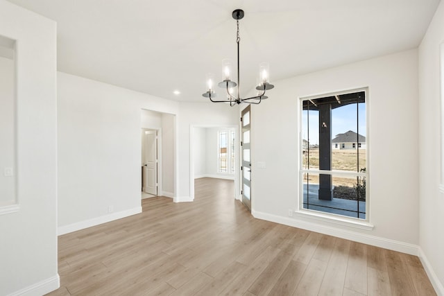 unfurnished dining area featuring a notable chandelier and light hardwood / wood-style flooring