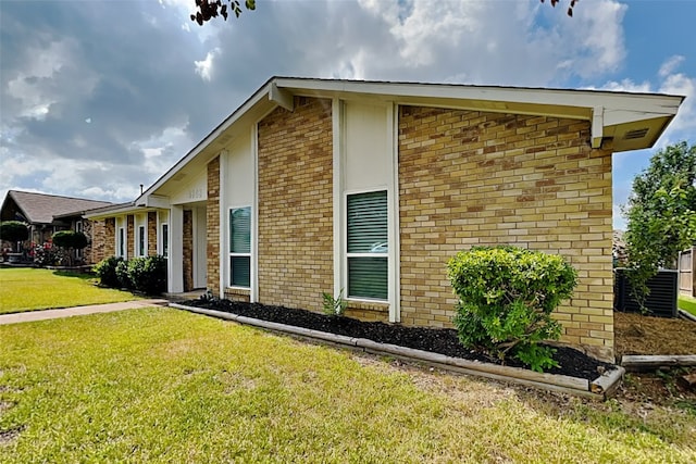 view of side of home with brick siding and a yard