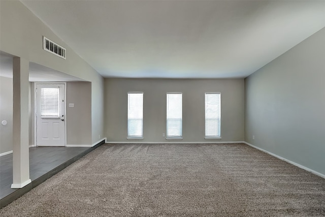 unfurnished room featuring dark colored carpet, a wealth of natural light, and visible vents