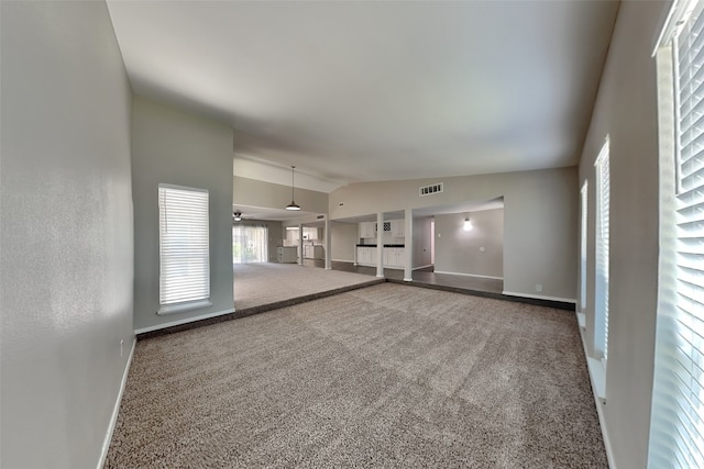 carpeted spare room featuring vaulted ceiling, visible vents, and baseboards