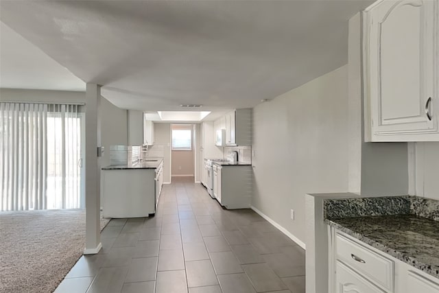 kitchen with tile patterned flooring, white gas range oven, white cabinets, and carpet flooring