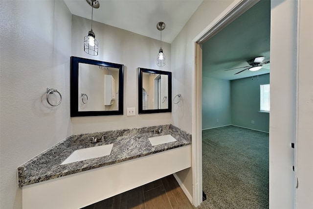 bathroom featuring double vanity, wood finished floors, a sink, and a ceiling fan