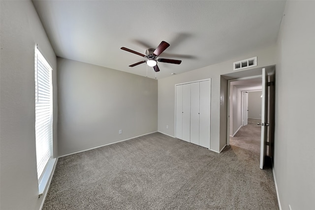 unfurnished bedroom with a ceiling fan, carpet, visible vents, and a closet