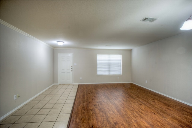 empty room featuring light tile patterned floors and crown molding