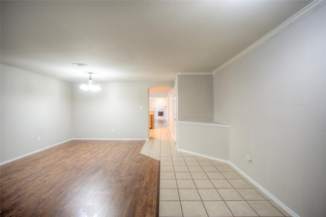 spare room with light wood-type flooring, ornamental molding, and a chandelier