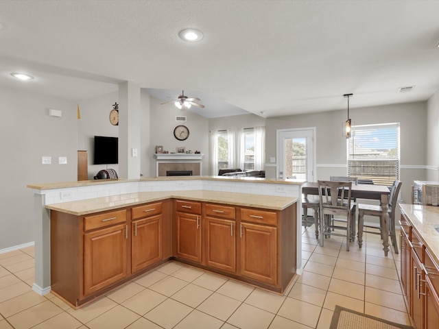 kitchen with hanging light fixtures, a healthy amount of sunlight, light tile patterned floors, and a tile fireplace