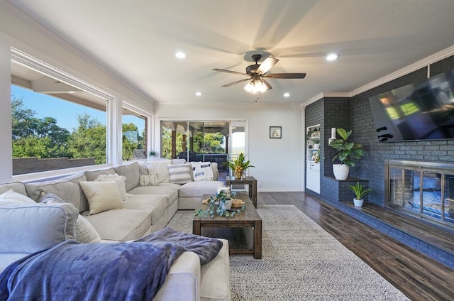 living room featuring ceiling fan, a fireplace, dark hardwood / wood-style floors, and crown molding