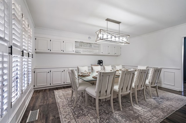 dining area featuring ornamental molding, dark wood-type flooring, and a chandelier