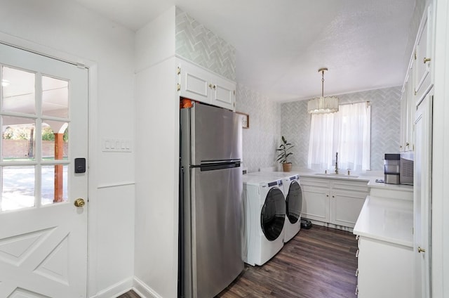 clothes washing area featuring dark wood-type flooring, separate washer and dryer, a notable chandelier, and sink