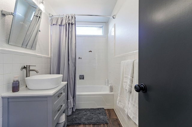 bathroom with hardwood / wood-style floors, vanity, backsplash, shower / bathtub combination with curtain, and tile walls