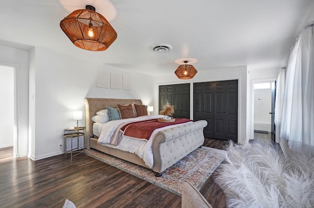 bedroom with dark hardwood / wood-style flooring and two closets