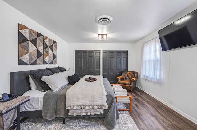 bedroom featuring dark wood-type flooring and two closets