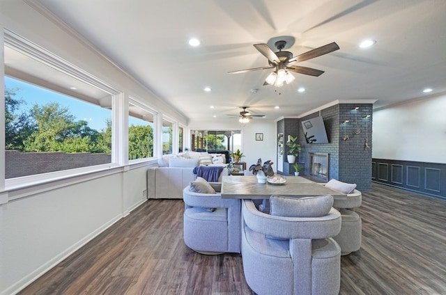 living room with a fireplace, dark wood-type flooring, crown molding, and ceiling fan