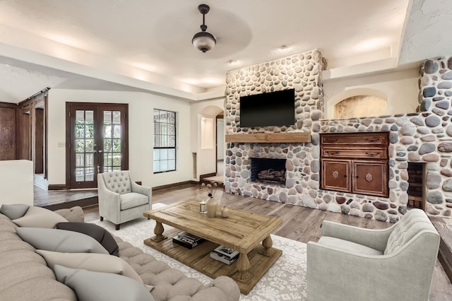 living room with a fireplace, french doors, and light wood-type flooring