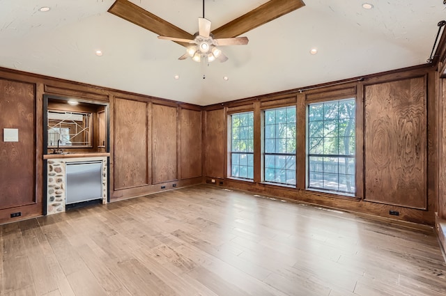 unfurnished living room featuring ceiling fan, wooden walls, and light hardwood / wood-style flooring