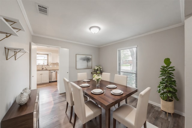 dining room with a wealth of natural light, hardwood / wood-style floors, and crown molding