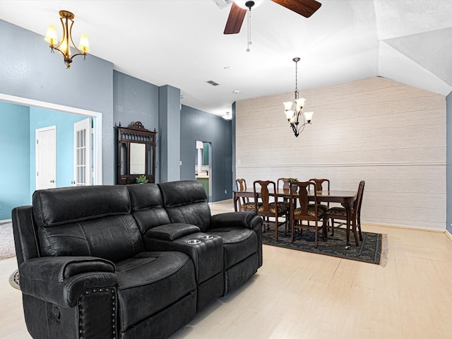 living area with visible vents, vaulted ceiling, light wood-style flooring, and ceiling fan with notable chandelier