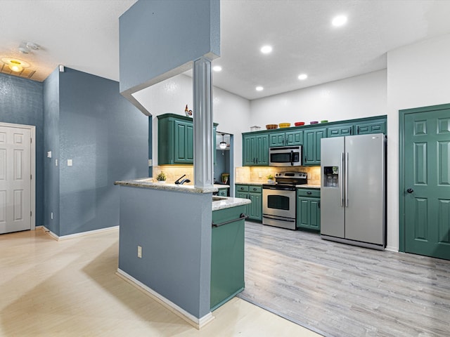 kitchen with light wood-type flooring, green cabinetry, backsplash, kitchen peninsula, and stainless steel appliances