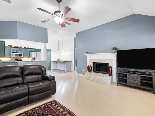 living room with vaulted ceiling, light hardwood / wood-style flooring, a brick fireplace, and ceiling fan