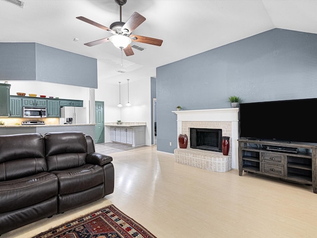 living area with lofted ceiling, ceiling fan, light wood-style flooring, visible vents, and a brick fireplace