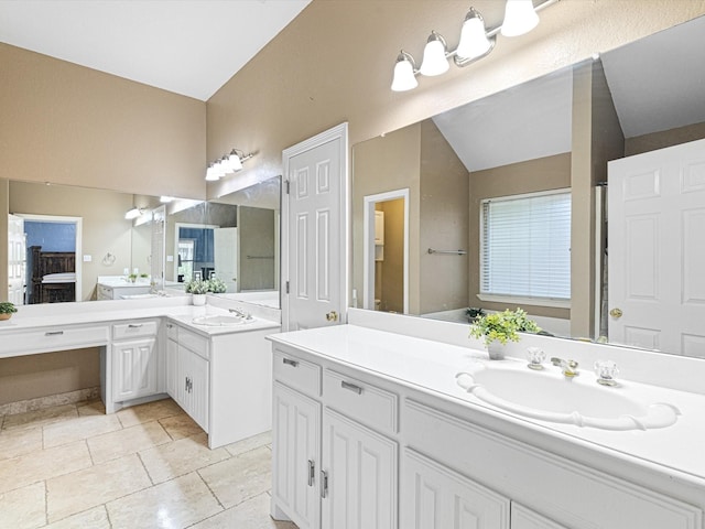 bathroom with two vanities, vaulted ceiling, and a sink