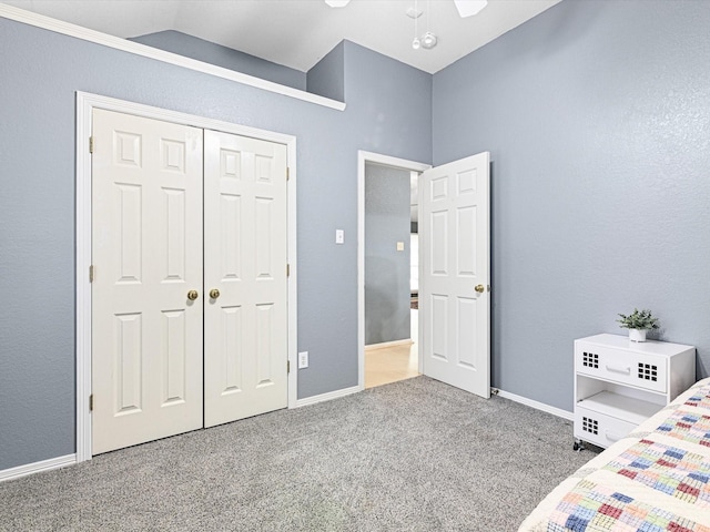 unfurnished bedroom featuring vaulted ceiling, a closet, carpet, and baseboards