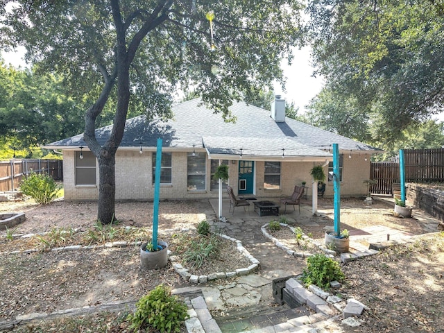 back of property featuring a shingled roof, a patio, a chimney, fence, and brick siding