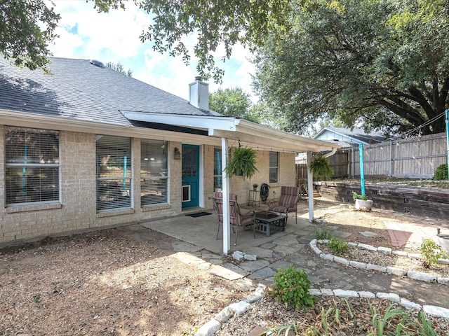 back of property with a patio area, a chimney, fence, and roof with shingles