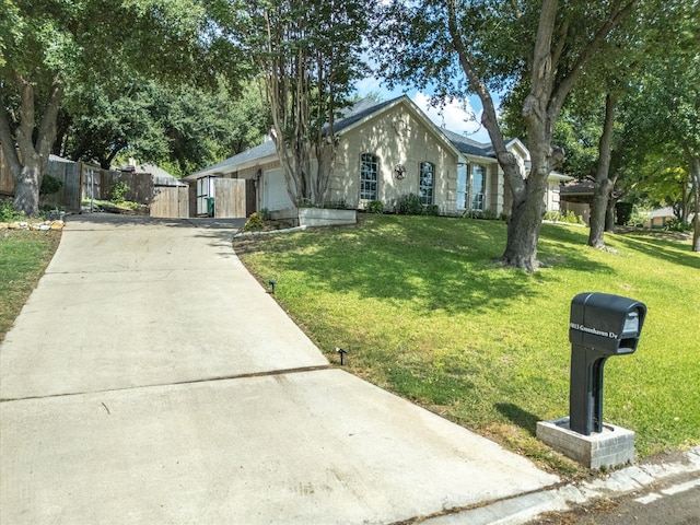 view of front of home with an attached garage, driveway, and a front lawn