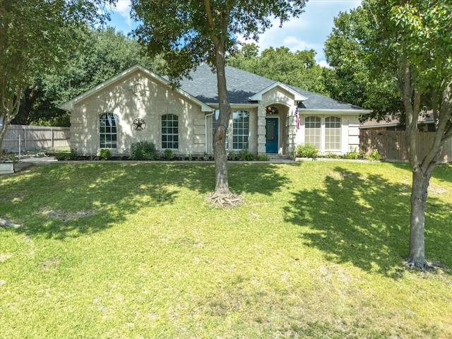 single story home featuring fence, a front lawn, and roof with shingles