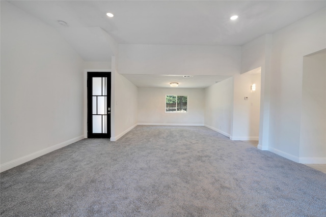 carpeted spare room with vaulted ceiling