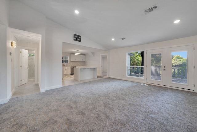 unfurnished living room featuring high vaulted ceiling, sink, light carpet, and french doors