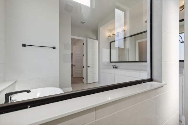 bathroom with vanity, a tub to relax in, and tile walls