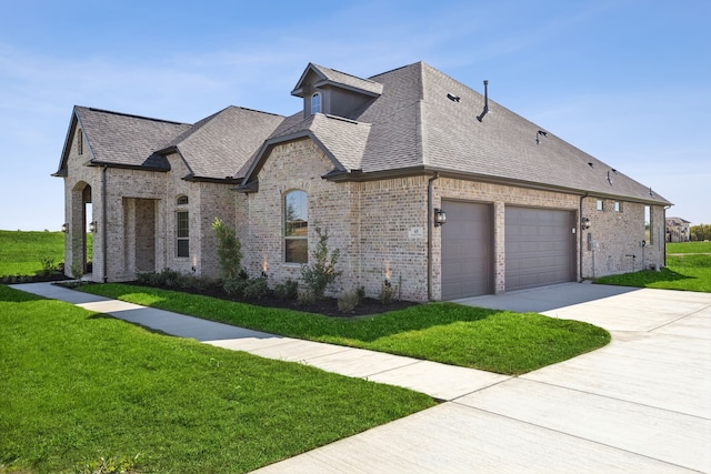 french provincial home featuring a front yard and a garage