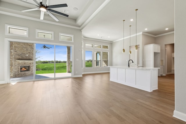 kitchen featuring a kitchen island with sink, light hardwood / wood-style flooring, ceiling fan, decorative light fixtures, and white cabinetry